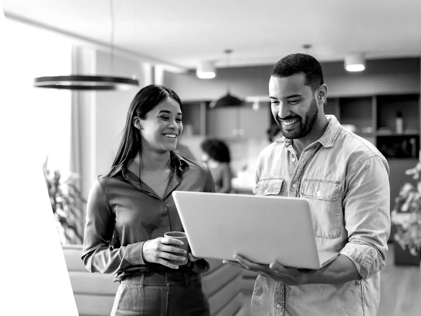 Two coworkers standing and collaborating over a laptop.